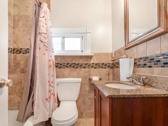 a bathroom with a granite countertop sink a toilet and a mirror