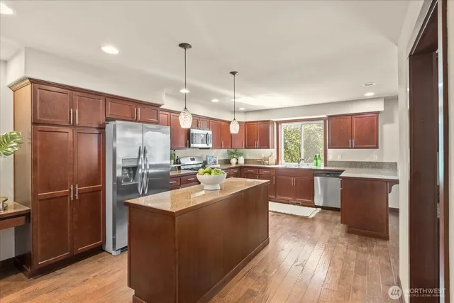 a kitchen with stainless steel appliances a refrigerator a sink dishwasher a oven with wooden cabinets and wooden floor
