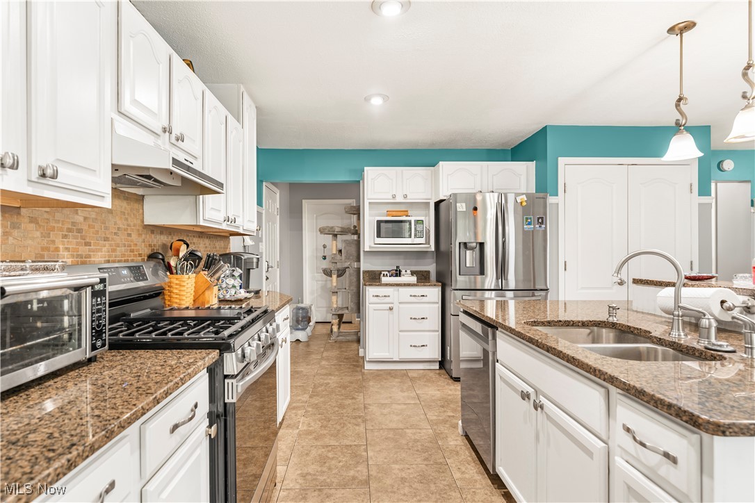 155 Ridgewood Boulevard Belpre, OH 45714 - Photo 22 of 49 Kitchen with stainless steel appliances, white cabinetry, hanging light fixtures, light tile patterned flooring, and dark stone countertops