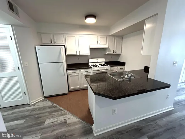 a kitchen with a sink a refrigerator a microwave and cabinets