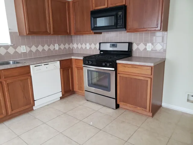 a kitchen with granite countertop white cabinets stainless steel appliances and a sink