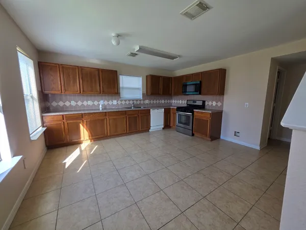 a large kitchen with a stove a sink dishwasher and a refrigerator