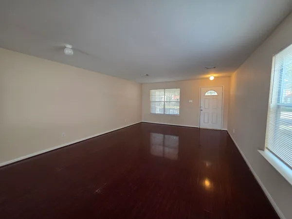 an empty room with wooden floor and windows