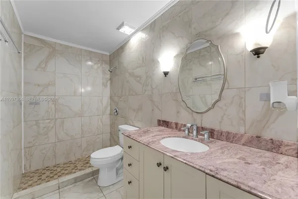 a bathroom with a granite countertop sink a toilet a mirror and shower