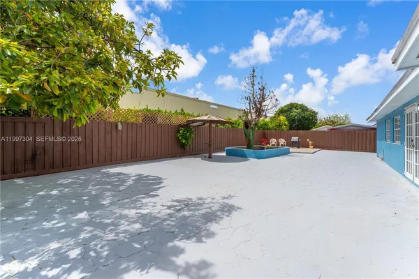 a backyard of a house with table and chairs and wooden fence