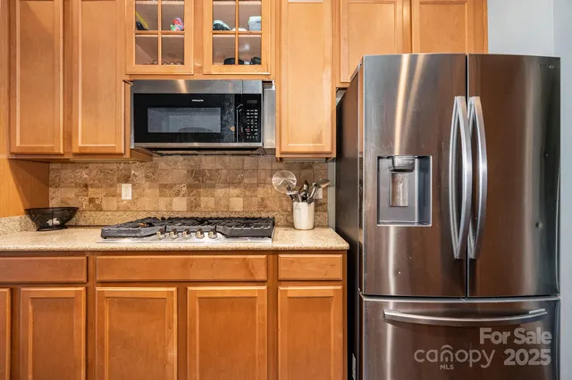 a kitchen with stainless steel appliances granite countertop a refrigerator a stove and a sink with wooden cabinets