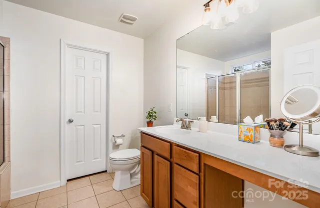 a spacious bathroom with a granite countertop sink a toilet a mirror and vanity