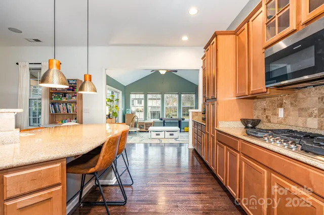 a kitchen with stainless steel appliances a stove a sink a dining table and chairs with wooden floor