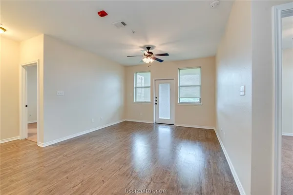 a view of an empty room with a window and wooden floor