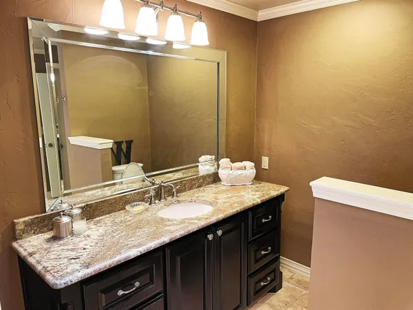 a bathroom with a granite countertop sink and a mirror