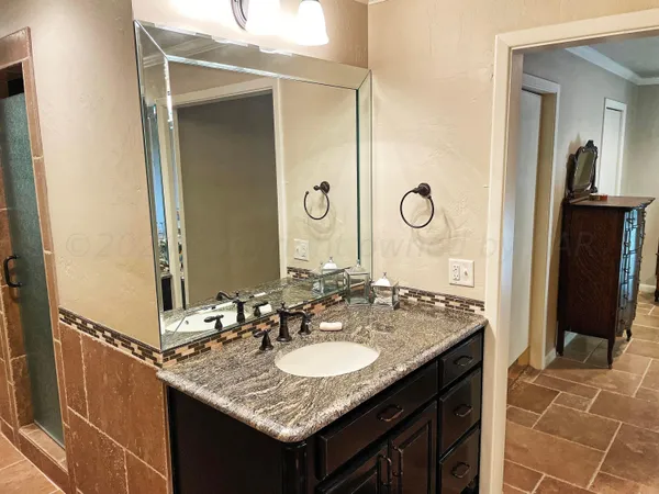 a bathroom with a granite countertop sink a mirror and a shower