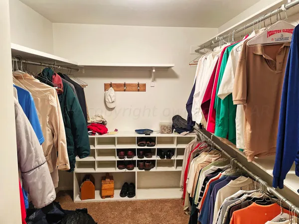 a view of walk in closet with clothes and shoes