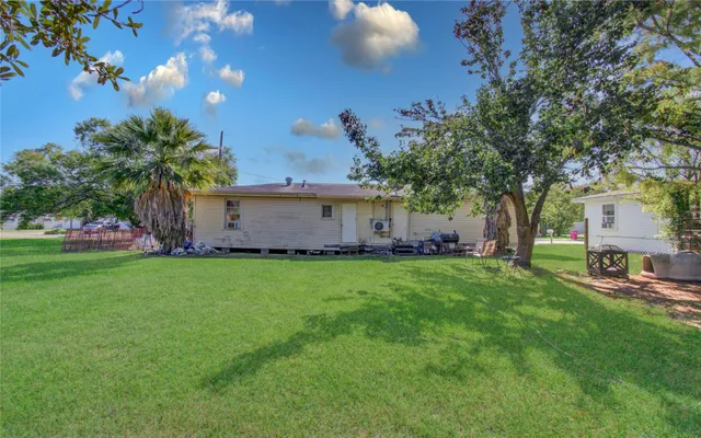 a view of a backyard with table and chairs and potted plants and large tree