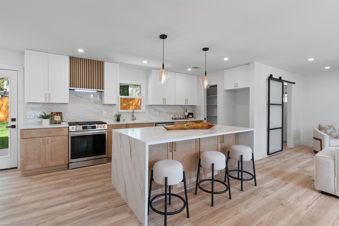 5604 Overbrook Drive Austin, TX 78723 - Photo 9 of 34 a kitchen with granite countertop a table chairs stove a refrigerator and cabinets