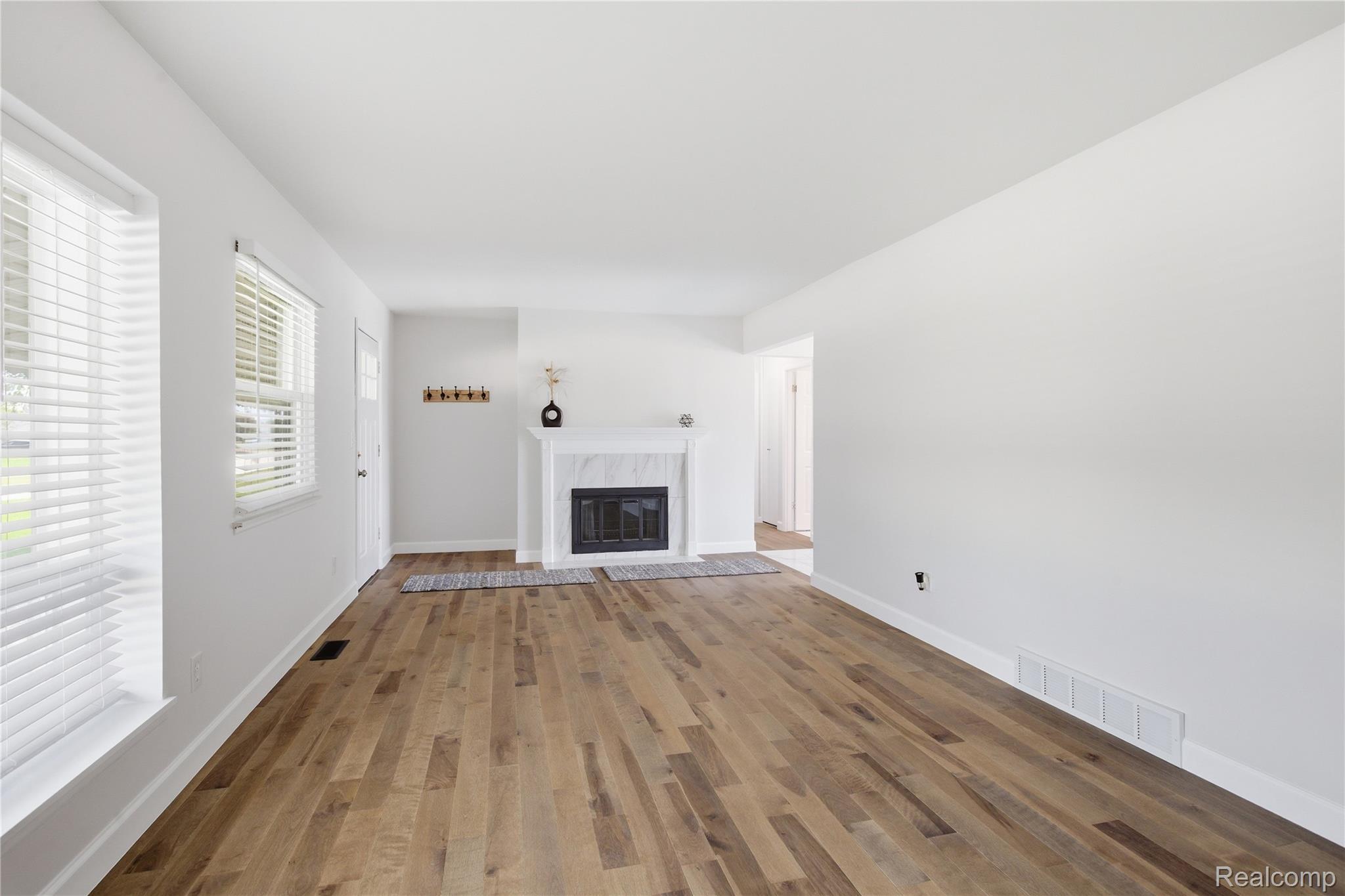 37257 Dundee Street Sterling Heights, MI 48310 - Photo 8 of 47 Living area featuring wood-finish flooring, a white mantel fireplace with a dark firebox, and white window blinds