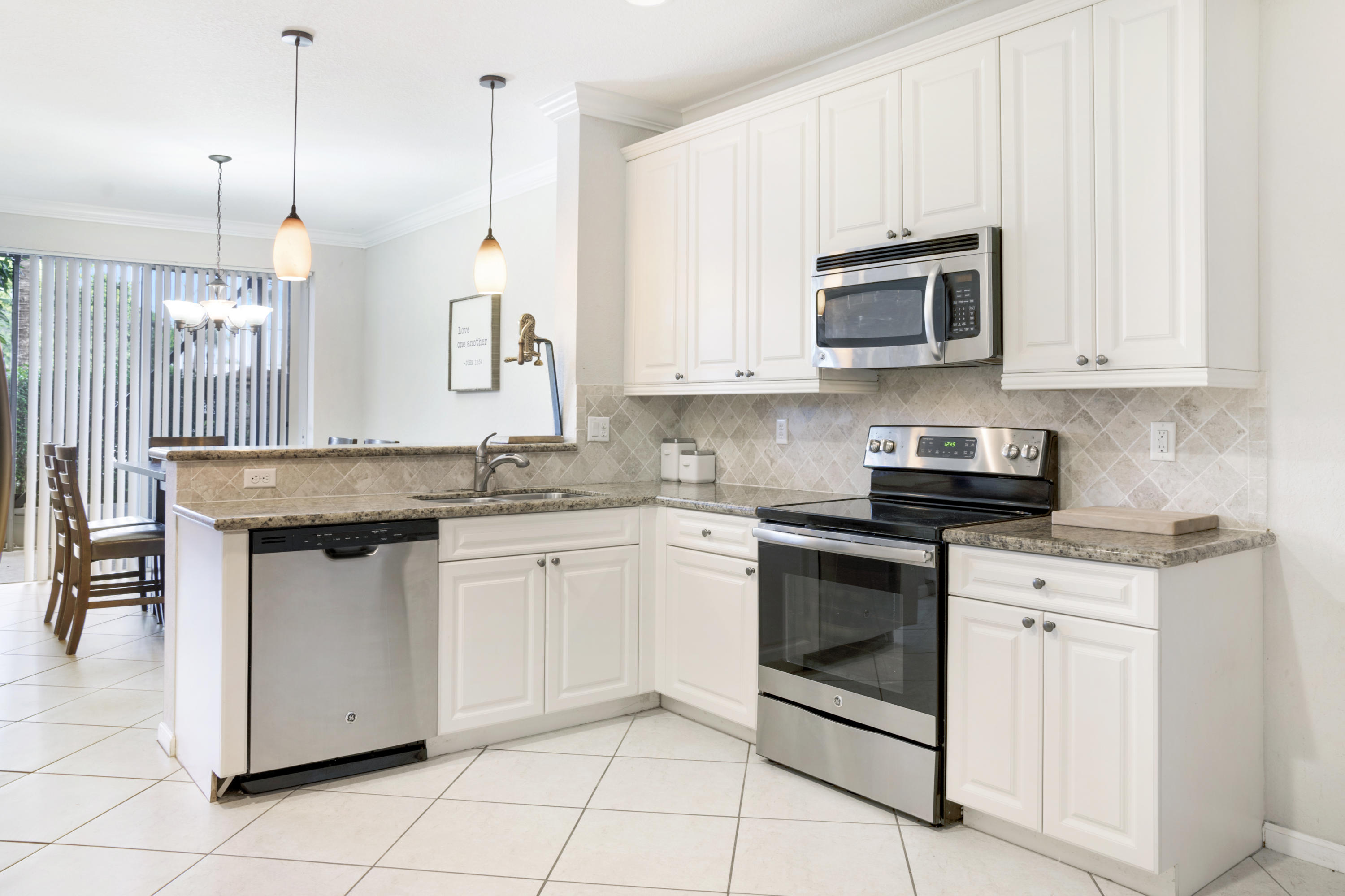 4719 North Prive Circle Delray Beach, FL 33445 - Photo 6 of 23 a kitchen with stainless steel appliances granite countertop a stove a sink and white cabinets