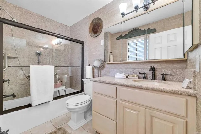 a bathroom with a granite countertop sink a toilet and a mirror