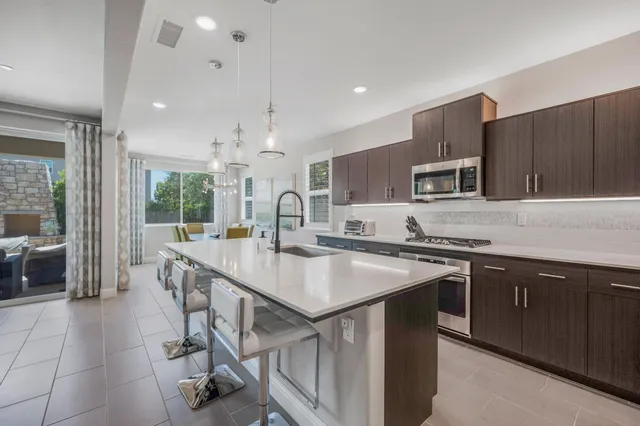 a kitchen with stainless steel appliances granite countertop a stove a sink a microwave a refrigerator and cabinets