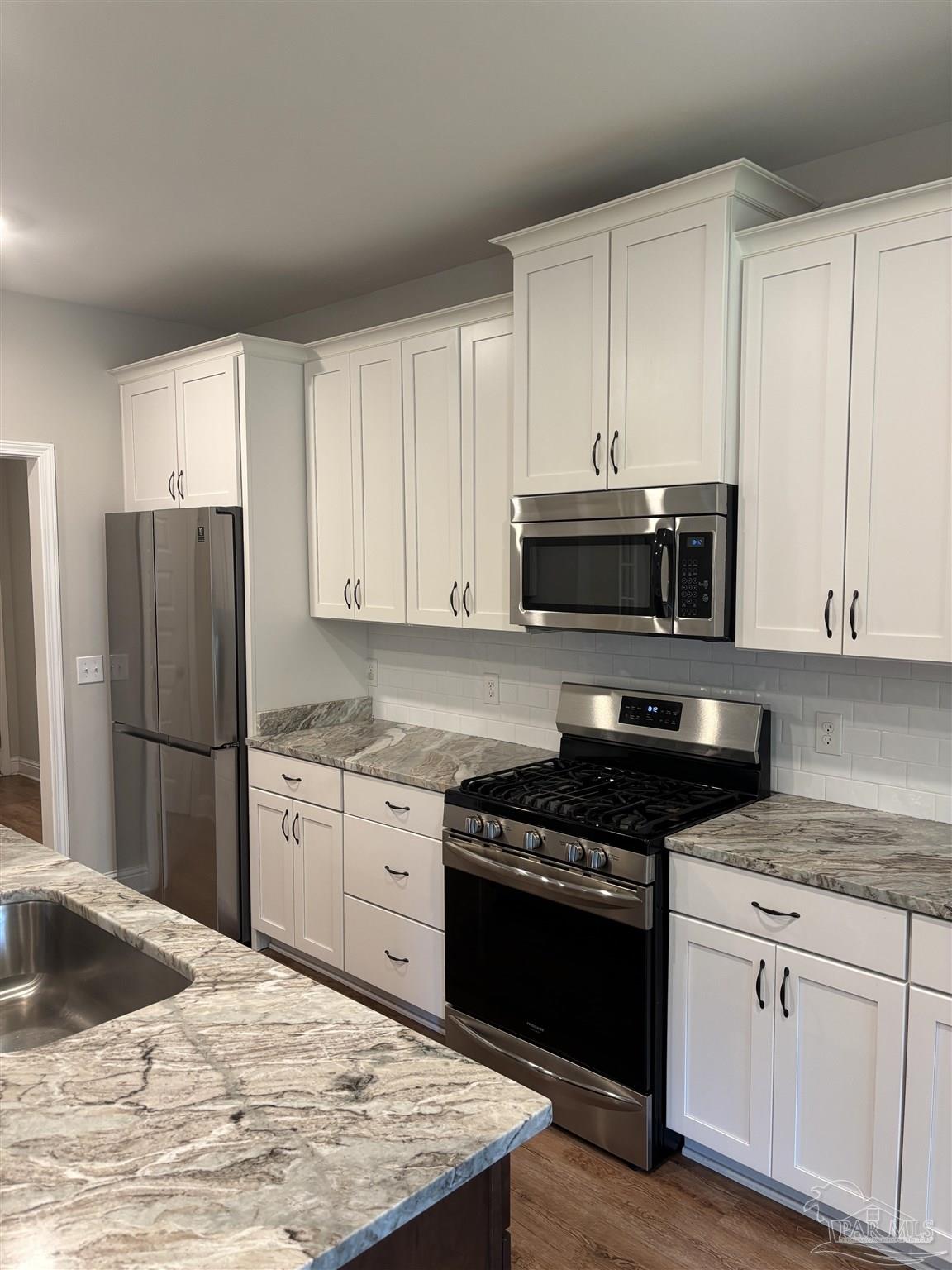 400 Broadleaf Circle Cantonment, FL 32533 - Photo 5 of 21 a kitchen with granite countertop a refrigerator stove and microwave