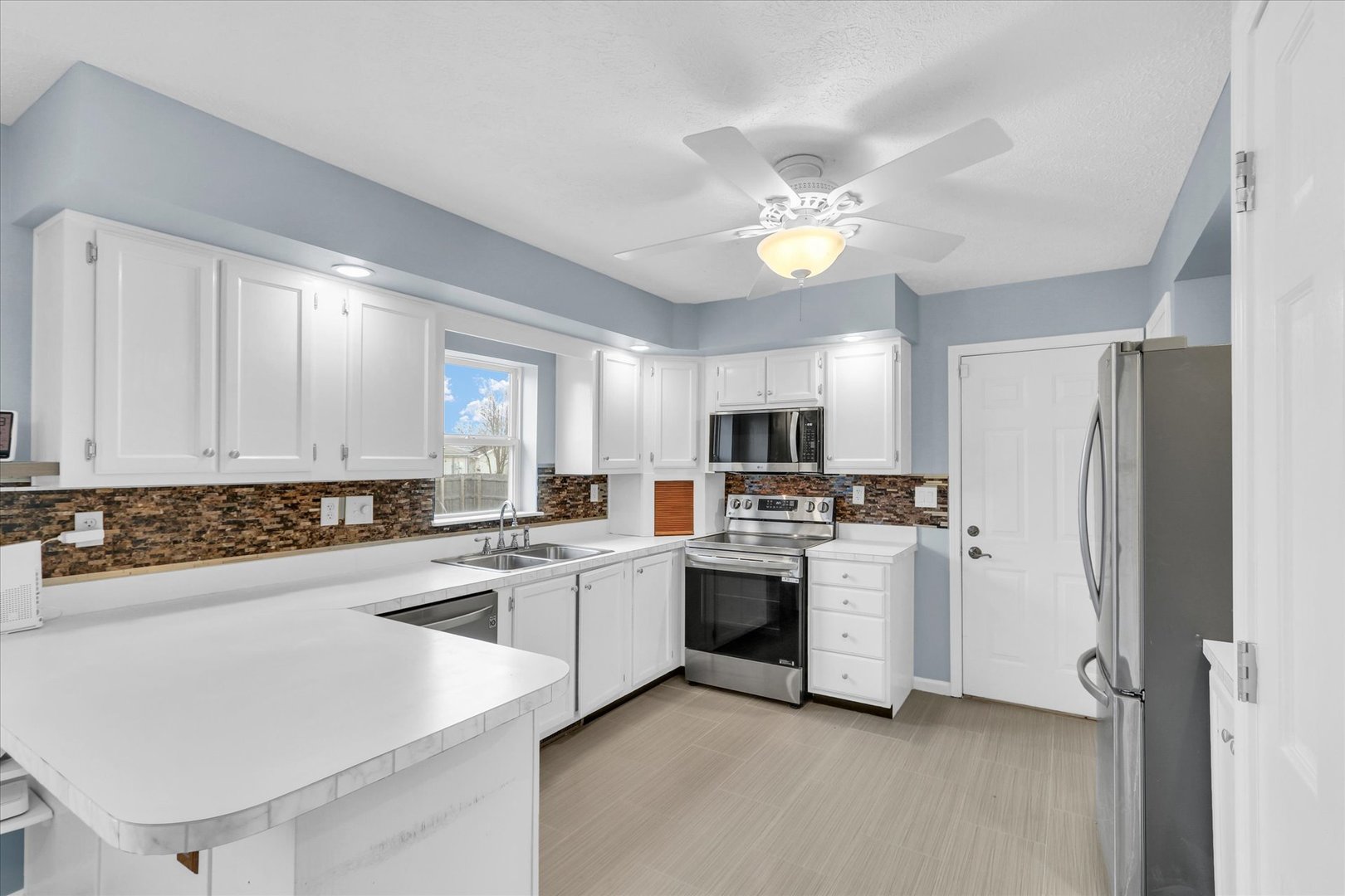 2302 Pheasant Ridge Road Mahomet, IL 61853 - Photo 9 of 31 a kitchen with stainless steel appliances a stove a sink and a refrigerator