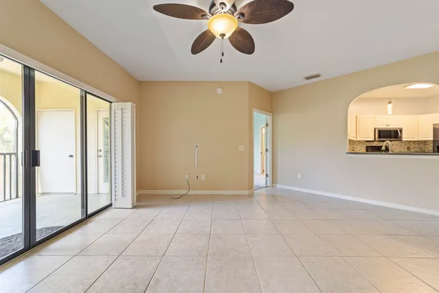 a view of an empty room and window with a ceiling fan