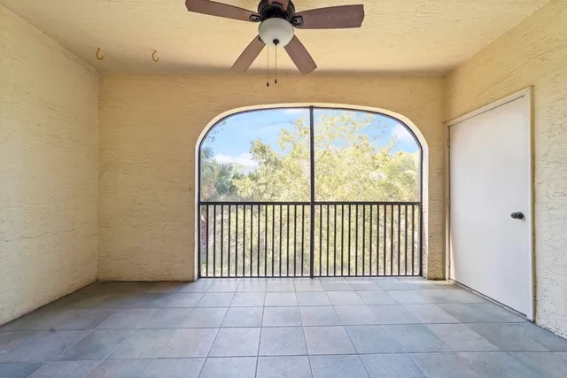 an empty room with windows and fan chandelier fan