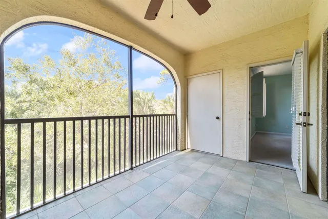 a view of an empty room with window and chandelier fan