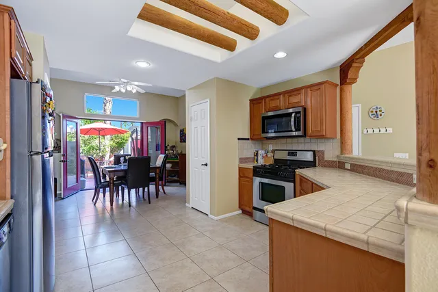 a kitchen with stainless steel appliances kitchen island granite countertop a table chairs microwave and sink