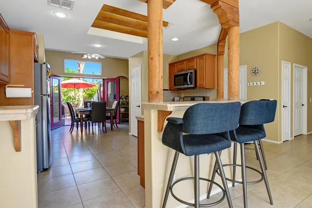 a dining hall with stainless steel appliances granite countertop a table and chairs with wooden floor