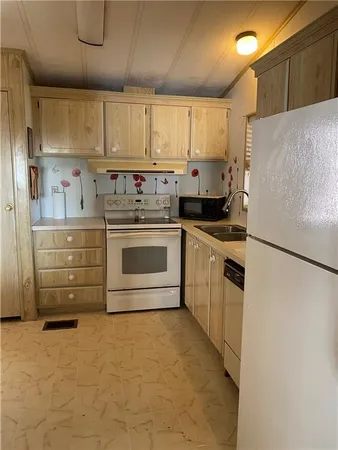 a kitchen with granite countertop a refrigerator stove and white cabinets