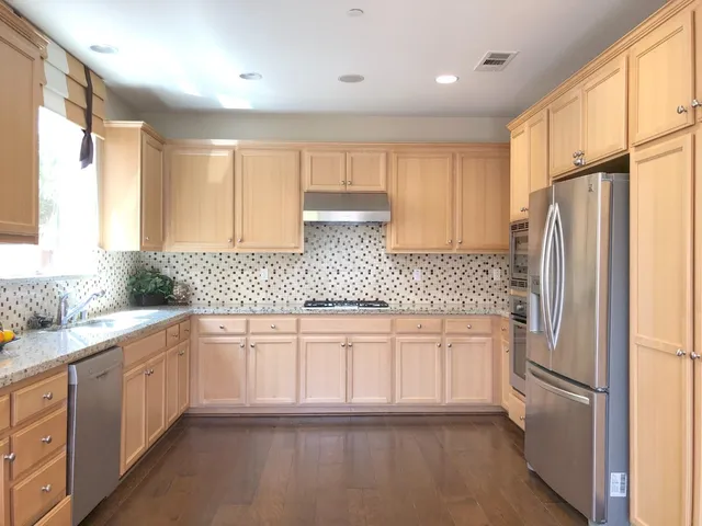a kitchen with granite countertop a refrigerator sink and cabinets