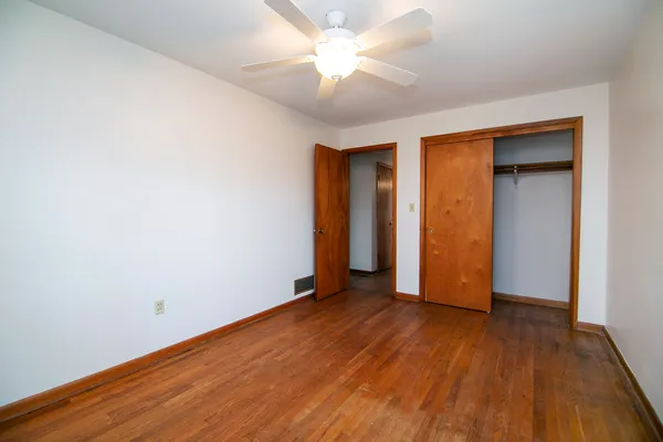 an empty room with wooden floor and a ceiling fan