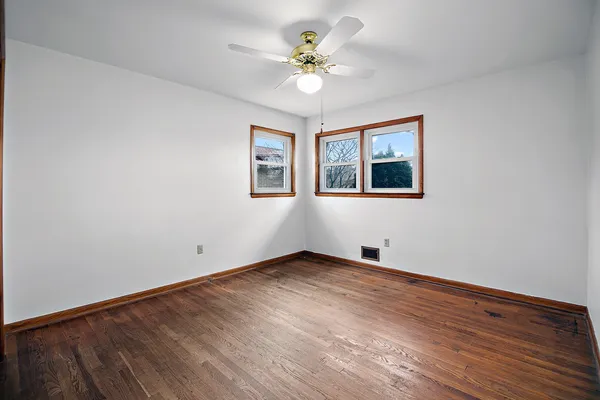 an empty room with wooden floor and ceiling fan