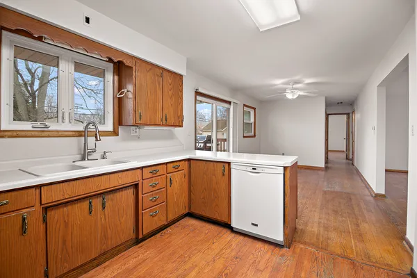 a kitchen with a sink cabinets wooden floor and a large window