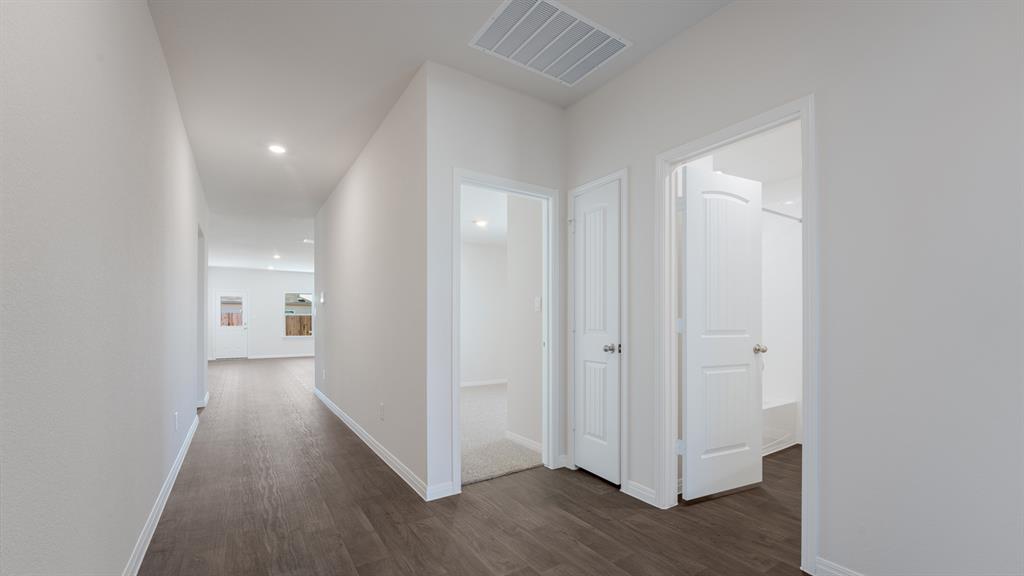 14021 Feinstein Street Manor, TX 78653 - Photo 6 of 25 A well-lit hallway with durable wood flooring guides you through this home's inviting layout.