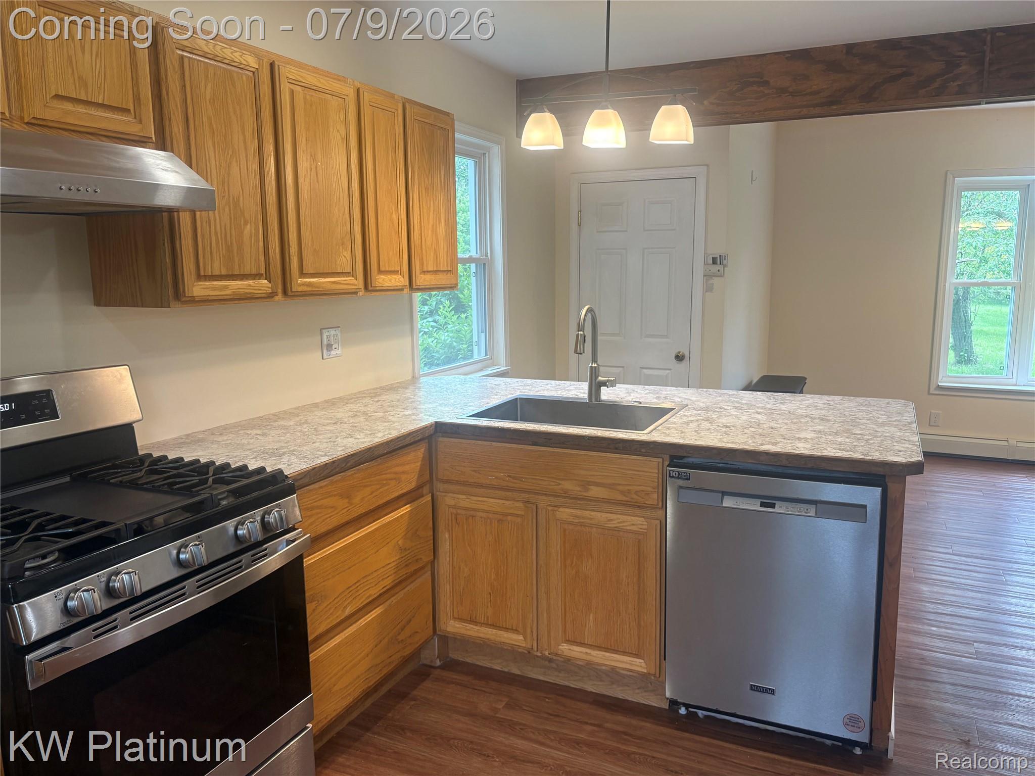 7280 North Road Fort Gratiot, MI 48059 - Photo 20 of 40 Kitchen featuring wood cabinetry, stainless steel appliances, a corner sink with a single-handle faucet, and a countertop extending to form a breakfast bar