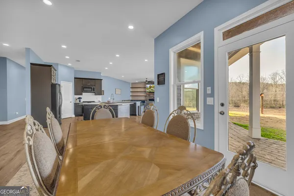 a kitchen with stainless steel appliances granite countertop wooden cabinets a sink a stove a dining table and chairs