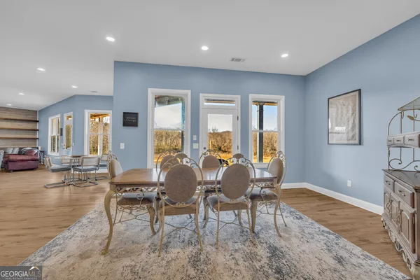 a dining room with furniture a large window and wooden floor