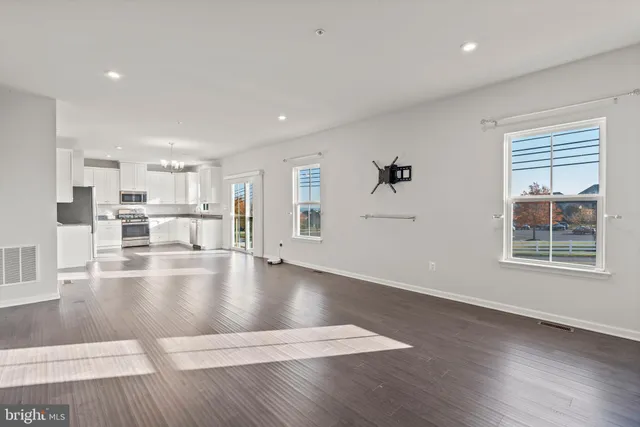 a kitchen with stainless steel appliances granite countertop a stove top oven a refrigerator a sink and dishwasher with wooden floor