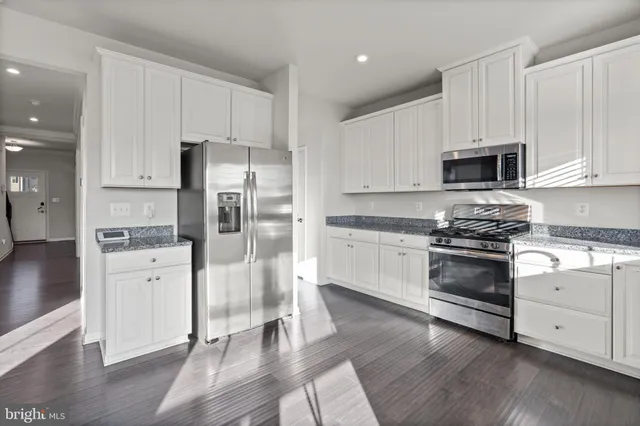 a kitchen with stainless steel appliances granite countertop a stove a sink and white cabinets