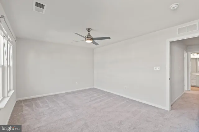 an empty room with a window and ceiling fan