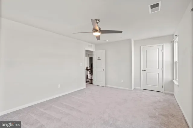 an empty room with a ceiling fan and carpet
