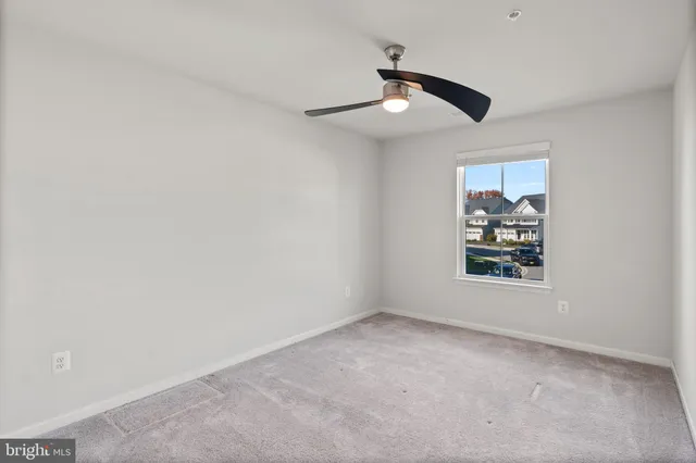 an empty room with windows and chandelier fan