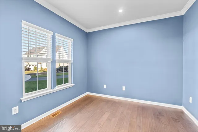 a view of an empty room with wooden floor and windows