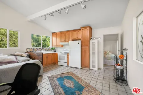 a backyard of a house with lots of plants and large tree