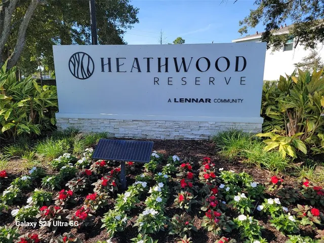a view of sign board with plants in the background
