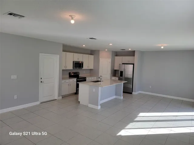 a large white kitchen with kitchen island a sink a stove a refrigerator and white cabinets