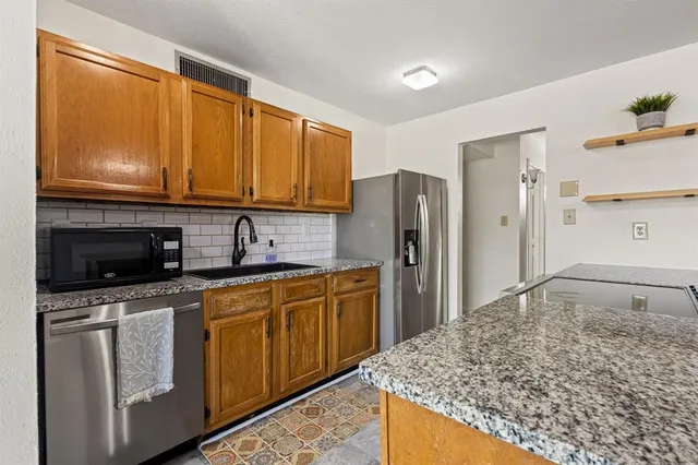 a kitchen with stainless steel appliances granite countertop a refrigerator and a stove top oven