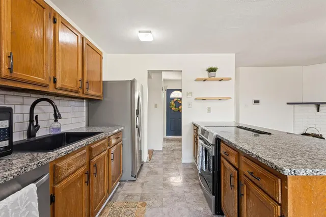 a kitchen with granite countertop a sink stove and refrigerator