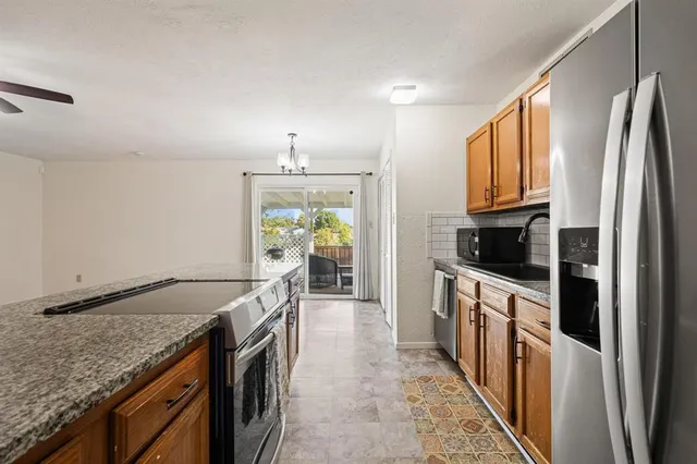a kitchen with granite countertop a sink stove and refrigerator